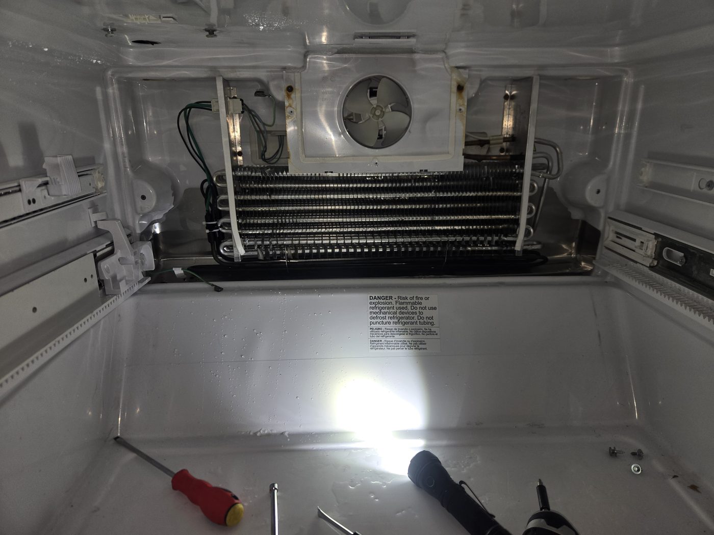 Refrigerator with the rear panel removed, exposing the evaporator coils