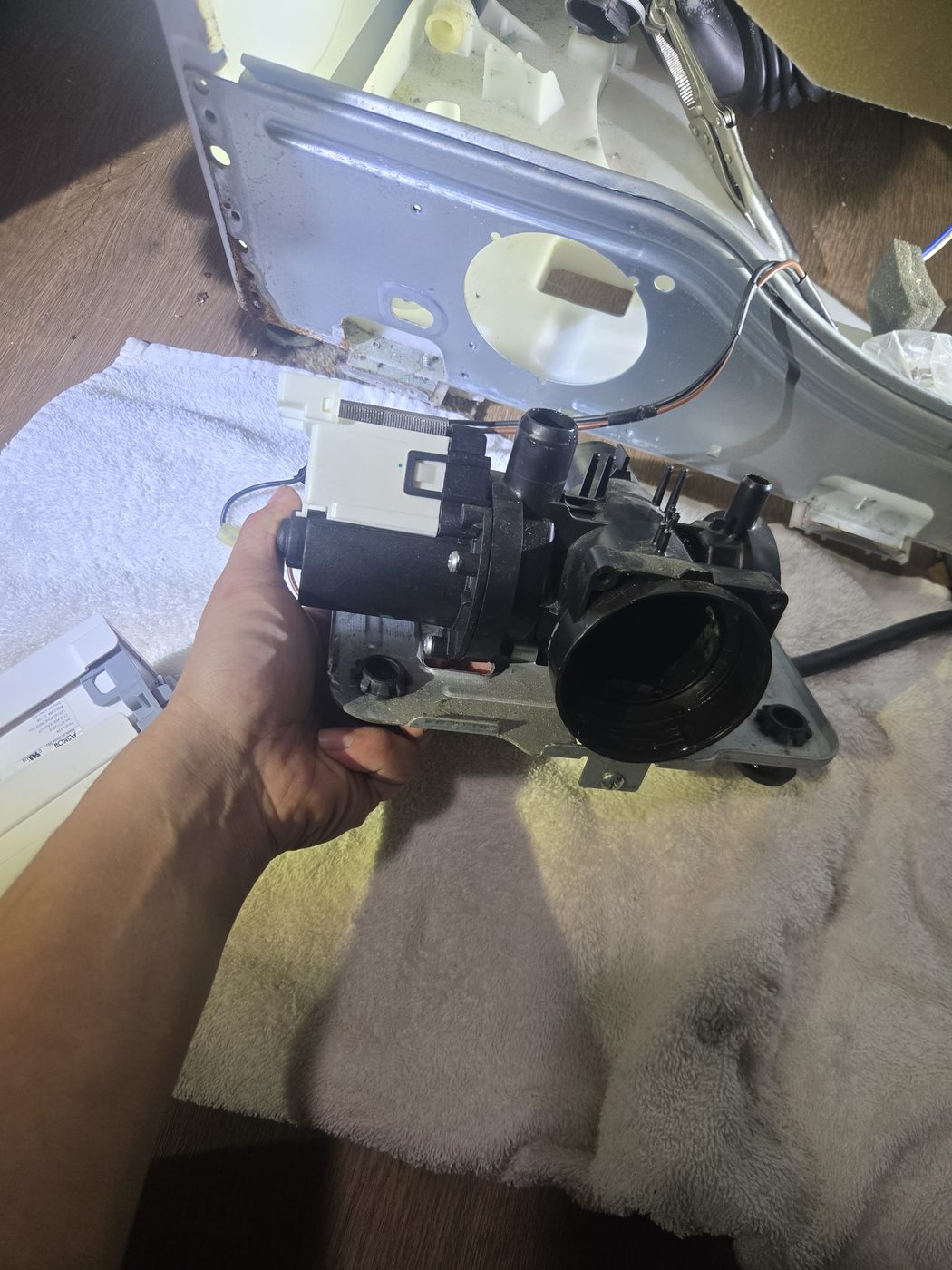 Technician holding a washer drain pump assembly removed for testing