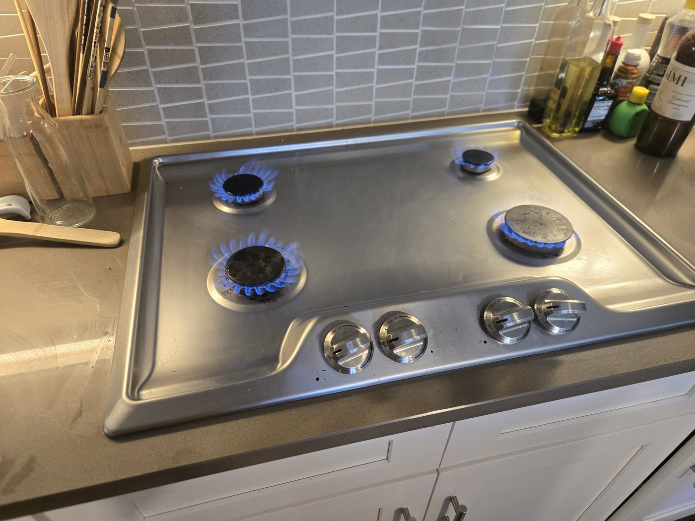 Stainless gas cooktop with burners lit after repair